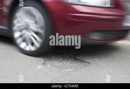 Un'automobile guida sopra un pothole su una strada in Kimberley, Nottingham Foto Stock