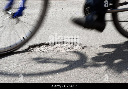 Stock di potole. Un ciclista corre sopra una buche su una strada a Kimberley, Nottingham Foto Stock