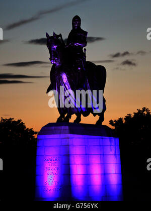 La statua di Robert the Bruce al tramonto come membri del pubblico e invitati ospiti a partecipare a una processione di fiaccolate per commemorare il 700° anniversario della battaglia di Bannockburn. Foto Stock