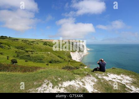 Un uomo vede le bianche scogliere di dover nel Kent, mentre le temperature sono impostate per salire, i funzionari sanitari hanno esortato le persone a prendersi cura del caldo estivo. Foto Stock