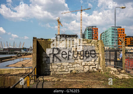 Refugee graffiti sul vecchio muro di fronte Barratt's Enderby Wharf di appartamenti di lusso e crociera terminale. Londra Foto Stock