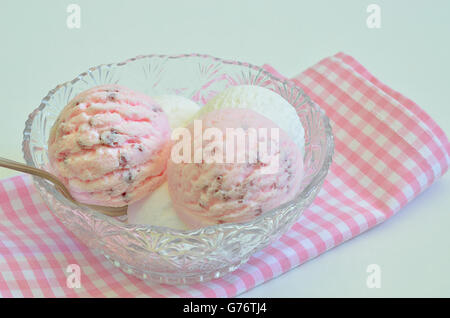 Palline di gelato alla fragola e gelato alla vaniglia in una ciotola su una bianca e rosa tovagliolo a scacchi, macro close up Foto Stock
