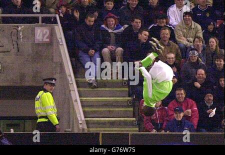 Un poliziotto guarda Julius Aghahowa della Nigeria eseguire acrobazie mentre celebra il suo obiettivo contro la Scozia durante il amichevole International Match al Pittodrie Stadium, Aberdeen, Scozia. Foto Stock