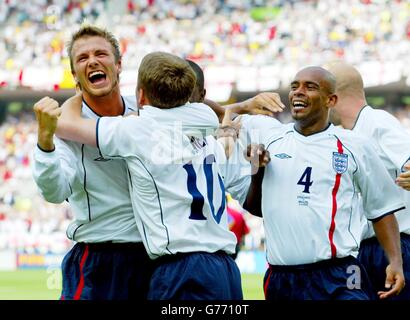 L'inglese Michael Owen (seconda a sinistra) festeggia con i compagni di squadra David Beckham (a sinistra) e Trevor Sinclair (a destra) dopo aver segnato contro il Brasile durante la quarta finale della Coppa del mondo all'Ecopa Stadium di Shizuoka, Giappone. Foto Stock