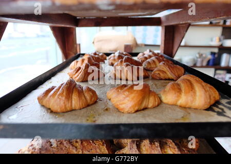 Croissant appena sfornati rinfrescarsi sul rack e di agire come un gustoso esca per i clienti a venire nel panificio a Hove. Foto Stock