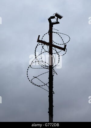 Guardando a voi. Cctv coperte di filo spinato contro uno scuro scuro. Foto Stock