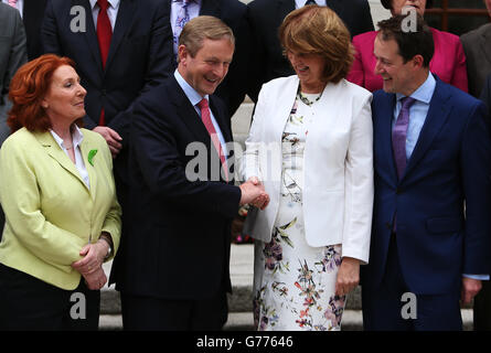 Taoiseach, Enda Kenny, stringe le mani con Tanaiste Joan Burton insieme ai ministri di stato recentemente annunciati Kathleen Lynch (a sinistra) e Sean Sherlock (a destra) in un'occasione fotografica presso gli edifici governativi di Dublino. Foto Stock