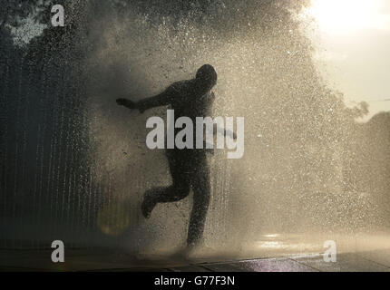 Un uomo completamente vestito esce dalla fontana d'acqua di Jeppe Hein's apparendo Rooms sulla Southbank, a Londra. Foto Stock