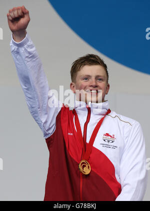 L'inglese Adam ha pelato con la sua medaglia d'oro dopo aver vinto il Breastroke Mens 100m al Tollcross Swimming Center durante i Giochi del Commonwealth 2014 a Glasgow. Foto Stock