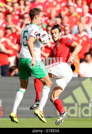 Il Galles Gareth Bale (destra) colpisce la palla verso il braccio di in Irlanda del Nord la Jonny Evans (a destra) durante il giro di 16 corrispondono al Parc de Princes, Parigi. Foto Stock