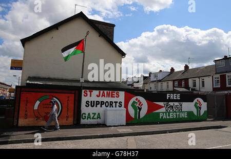 Un giovane ragazzo cammina davanti a un murale pro-palestinese a Belfast ovest, mentre i gruppi Loyalist e Repubblicani assumono posizioni rivali di sostegno per Israele e Palestina durante l'attuale periodo di conflitto. Foto Stock