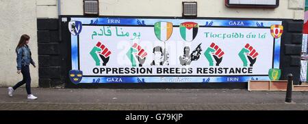 Una giovane donna passa accanto a un murale pro Palestina sulla Falls Road a Belfast, mentre i gruppi lealisti e repubblicani assumono posizioni rivali di sostegno per Israele e Palestina durante l'attuale riacutizzazione del conflitto. Foto Stock