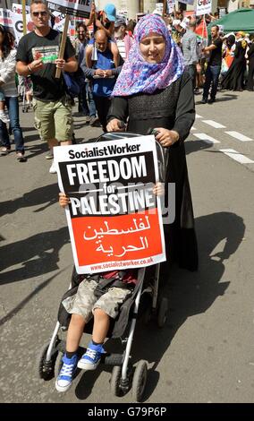 Una donna spinge la sua baia nel suo buggy durante una marcia pro-Palestina anti-Israele che ha iniziato presso l'edificio della BBC, prima di raggiungere Hyde Park nel centro di Londra. Foto Stock