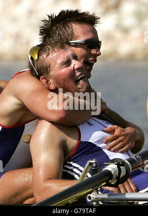 Il vogatore britannico James Cracknell abbracca quattro volte il medalista d'oro olimpico Matthew Pinsent (fronte) dopo che la squadra britannica ha vinto la finale di canottaggio maschile durante i Giochi Olimpici 2004 al Centro di canottaggio olimpico di Schinias ad Atene. Foto Stock