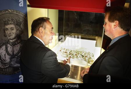 Il primo ministro Alex Salmond parla con il dipendente della storica Scozia Douglas Wilson mentre vede una copia della dichiarazione di Arbroath, durante una visita all'abbazia di Arbroath in Scozia. Foto Stock