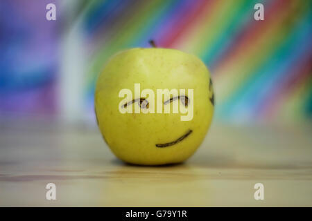 Photograh di un Apple con una felice volto sorridente e colorato sfondo sfocato Foto Stock