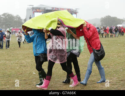 I festaioli riparano dalla pioggia durante il secondo giorno del V Festival, all'Hylands Park di Chelmsford, Essex. Foto Stock