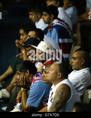 Shah, padre di Amir Khan (testa in mano, Union Jack sulle spalle), guarda la vittoria del primo turno di suo figlio, su Jong Sub Baik di Corea, nella quarta finale della Light 60kg Olympic Boxing Competion al Peristeri Oylpic Boxing Hall di Atene. L'uomo in cricket è Shahid Mahmood, zio di Amir. Foto Stock