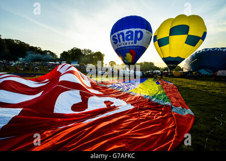 I mongolfiera vengono gonfiati prima di una salita di massa alla 36a edizione della festa internazionale delle mongolfiere presso l'Ashton Court Estate vicino a Bristol, che è il più grande evento di mongolfiera d'Europa. Foto Stock