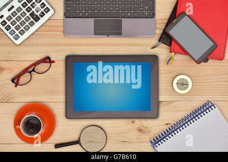 Tavoletta digitale con schermo vuoto e molti oggetti business sulla scrivania in legno. Foto Stock