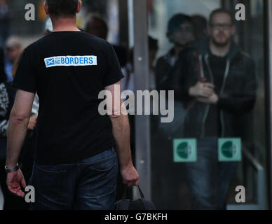 Un uomo che indossa un voto No Borders t-shirt cammina in Princes Street a Edimburgo come il sole tramonta questa sera. Foto Stock