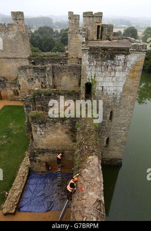 I tecnici di accesso alle corde prelevano le erbacce a mano dalle pareti del castello di Bodiam nel Sussex orientale per contribuire a mantenere la pietra arenaria medievale come parte del lavoro di conservazione in corso. Foto Stock