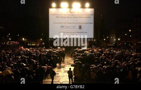 La folla attende sotto la pioggia prima che i PET Shop Boys eseguano un nuovo punteggio per il classico film del 1925 "Battleship Potemkin" con la famosa Dresden Sinfoniker a Trafalgar Sqaure, nel centro di Londra. L'evento è il momento culminante del programma estivo di Trafalgar Square, con oltre 10,000 persone attese. Foto Stock
