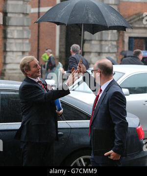 Taoiseach Enda Kenny (a sinistra) rifiuta l'uso di un ombrello quando arriva per una riunione del Consiglio ministeriale Nord Sud al Castello di Dublino, Irlanda. Foto Stock