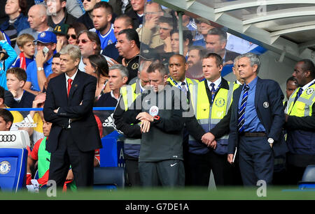 Arsenal manager Arsene Wenger (a sinistra) in discussione con il quarto ufficiale Jon Moss (al centro) sulla linea di contatto come il manager del Chelsea Jose Mourinho (a destra) guarda avanti durante la partita della Barclays Premier League a Stamford Bridge, Londra. Foto Stock