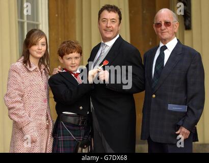 John Boyle (al centro) a Buckingham Palace, dopo aver raccolto il suo MBE per i servizi a Drama dalla Regina Elisabetta II della Gran Bretagna, raffigurato con suo padre Hugh (a destra), figlia Iona 12 (a sinistra), e il figlio Dylan 10 (seconda a sinistra). Foto Stock