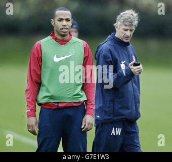 Thierry Henry di Arsenal (a sinistra) guarda allenarsi con il suo manager Arsene Wenger (a destra) controllando il suo cronometro durante l'allenamento a London Colney, vicino St Albans, Hertfordshire, prima di giocare il greco Panathinaikos lato domani nella partita UEFA Champions League Group E. Foto Stock