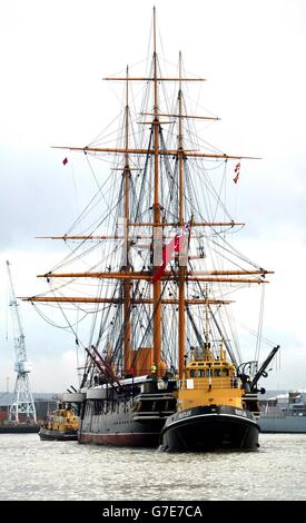 HMS Warrior, la prima nave da guerra britannica rivestita di ferro, è manuverata da rimorchiatori che oltrepassano le fregate della Royal Navy mentre si dirige verso il bacino secco a Portsmouth. La nave di 144 anni trascorre tre settimane per essere restaurata presso il cantiere navale della Marina. Foto Stock