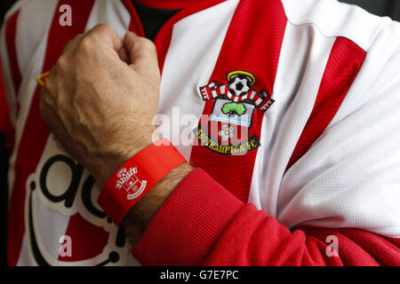 Un sostenitore di football di Southampton che indossa la sua banda di Bpay Barclaycard con il marchio del club. Saints è diventata la prima squadra di calcio a livello mondiale ad offrire ai fan esclusivi bpay band di marca club, Barclaycards nuovo dispositivo di pagamento indossabile senza contatto. I fan che utilizzano il dispositivo indossato dal polso per effettuare pagamenti avranno accesso a offerte fedeltà esclusive, esperienze speciali e concorsi a premi. Raffigurato prima della partita della Barclays Premier League al St. Mary's Stadium di Southampton. Foto Stock