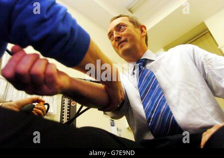 Il Ministro della Sanità John Hutton ha la pressione sanguigna assunta da un infermiere presso il Soho NHS Walk-in Centre presso il Soho Centre for Health & Care nel centro di Londra. Il signor Hutton si è recato in visita al centro, che fa parte del Westminster NHS Primary Care Trust, in quanto sono stati annunciati altri centri di assistenza, che saranno aperti in tutto il paese, vicino alle principali stazioni, dove i pendolari possono beneficiarne. Foto Stock