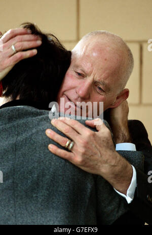 Lord Michael Cashman abbraccia un membro della congregazione dopo il servizio funebre del suo partner a lungo termine Paul Cottingham, presso il crematorio City of London, nel nord-est di Londra. Foto Stock