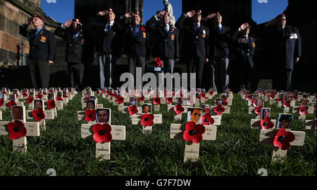 I veterani del Royal Engineer salutano accanto alle croci con le immagini dei militari uccisi nelle croci dell'Afganistan con le immagini dei militari uccisi in Afganistan durante il conflitto nel campo di ricordo di Poppyscotland accanto al Monumento Scott di Edimburgo. Foto Stock