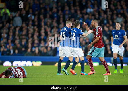 I tentatori si flettono tra i due lati dopo che James McCarthy di Everton (centro) porta giù Morgan Amalfitano di West Ham United (piano) per guadagnarsi una carta gialla durante la partita della Barclays Premier League al Goodison Park, Liverpool. Foto Stock