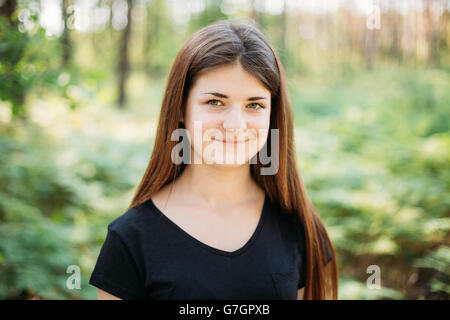 Close up ritratto di Felice i Capelli rossi ragazza caucasica giovane donna in estate foresta verde. Ragazza vestita in una T-shirt nera. Essere umano Foto Stock