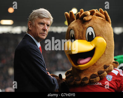 Calcio - Barclays Premier League - West Bromwich Albion / Arsenal - The Hawthorns. Arsene Wenger manager dell'Arsenal guarda come la mascotte di Albion West Bromwich arriva a scuotere le mani Foto Stock