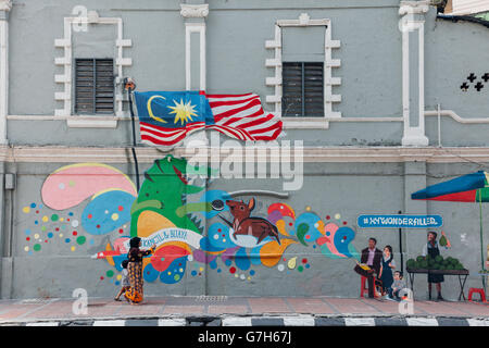 Donna in tradizionali abiti musulmani mostra arte di strada a suo figlio, Kuala Lumpur, Malesia Foto Stock