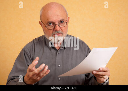 Uomo anziano, 59, tenendo una lettera, Bill, interrogando guardare Foto Stock