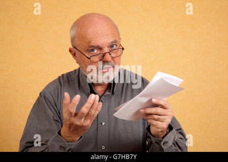 Uomo anziano, 59, tenendo una lettera, Bill, interrogando guardare Foto Stock