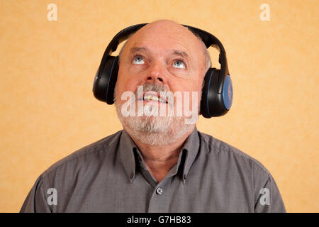 Uomo anziano, 59, con le cuffie, guardando verso l'alto Foto Stock