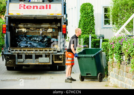 Soderkoping, Svezia - 20 Giugno 2016: Maschio garbage collector di laminazione a vuoto di un cestino della spazzatura torna a casa nel quartiere. Abito Foto Stock