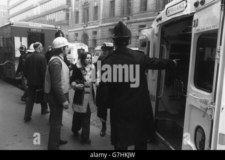 Un poliziotto londinese indica la strada come una donna azzardata, che è stata coinvolta nell'incidente della metropolitana alla stazione di Moorgate, è scortata in un'ambulanza. Foto Stock