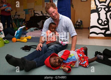 Il principe Harry gioca con due bambini piccoli (che stanno attraversando un programma per la malnutrizione) durante una visita all'organizzazione sostenuta da Sentebale 'toccare le vite minuscoli' a Maseru, Lesotho. Foto Stock