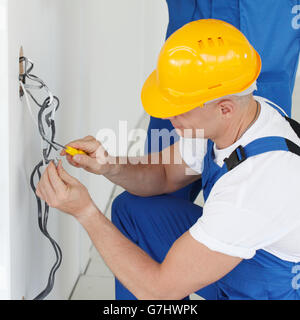 Due costruttori nei caschi che lavora con l'elettricità in ambienti interni Foto Stock