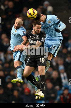 Danny Ings (centro) di Burnley combatte per la palla in aria con Martin Demechellis (a destra) e Pablo Zabaleta di Manchester City durante la partita della Barclays Premier League all'Etihad Stadium di Manchester. Foto Stock