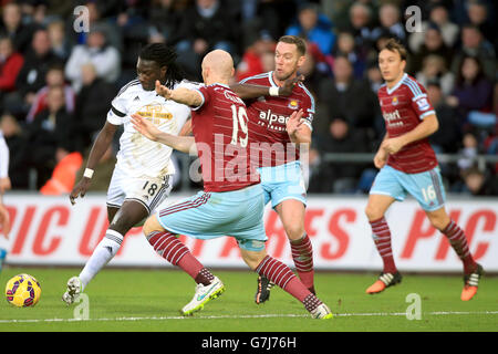 Il Bafetimbi Gomis di Swansea City (a sinistra) si scontra con Kevin Nolan di West Ham United e James Collins durante la partita della Barclays Premier League al Liberty Stadium di Swansea. Foto Stock