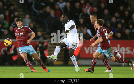 Il Bafetimbi Gomis di Swansea City tiene fuori James Tomkins di West Ham United (a sinistra), Winston Reid (seconda a destra) e Mark Noble (a destra) durante la partita della Barclays Premier League allo stadio Liberty di Swansea. Foto Stock